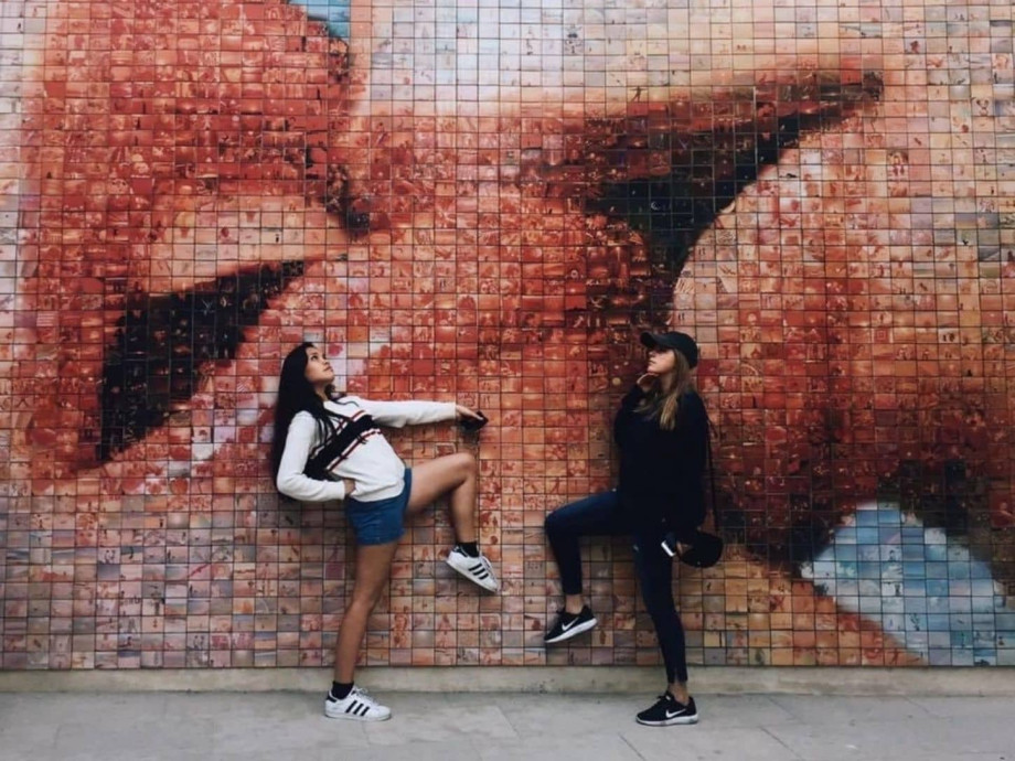 two girls posing in front of street art mural.