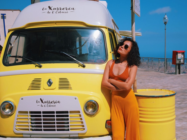 brightly coloured picture of woman standing in front of yellow churro truck