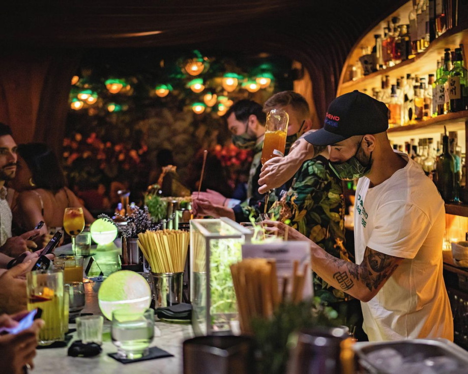 cocktail bartender preparing a drink in a dimly lit cocktail bar.