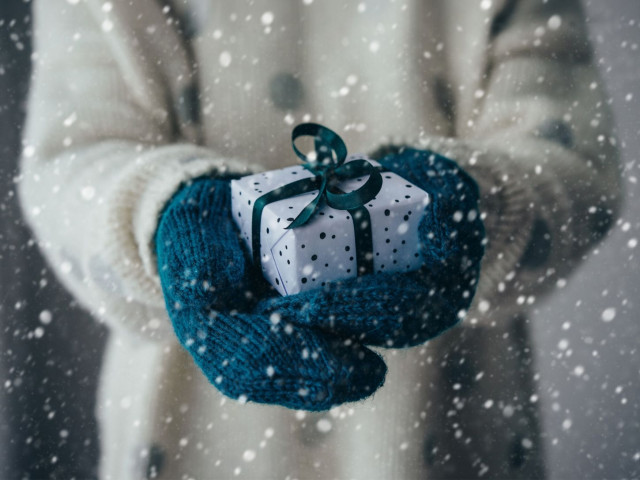 Hands in mittens holding out a gift.