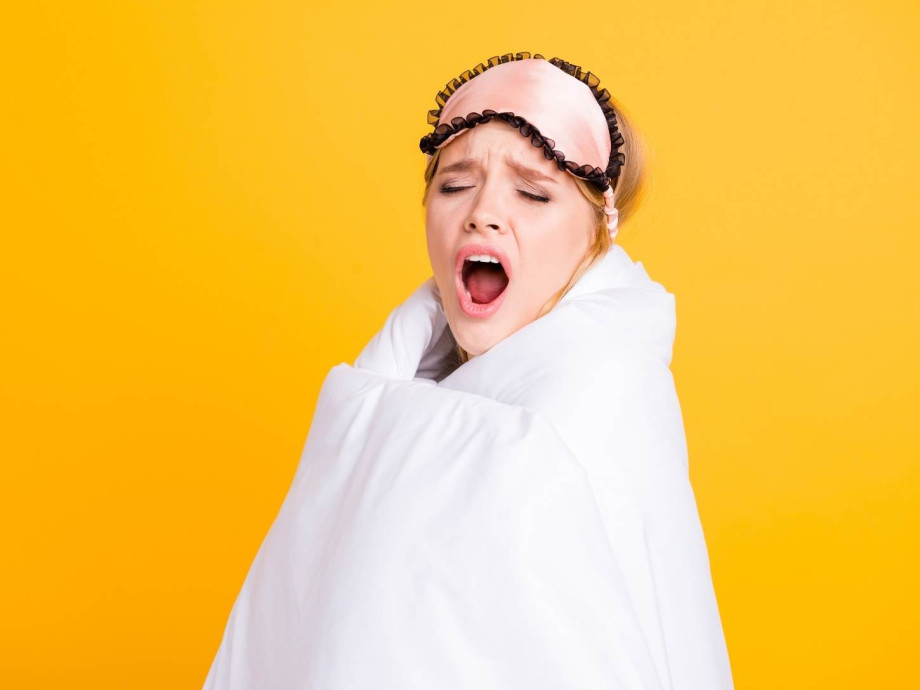 Yawning woman wrapped in duvet.
