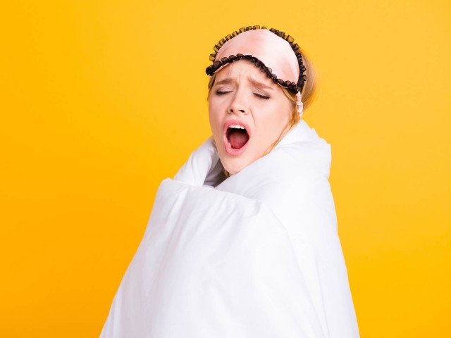 Yawning woman wrapped in duvet
