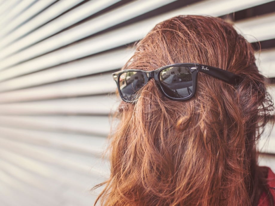 Person with long hair covering face and sunglasses over it.