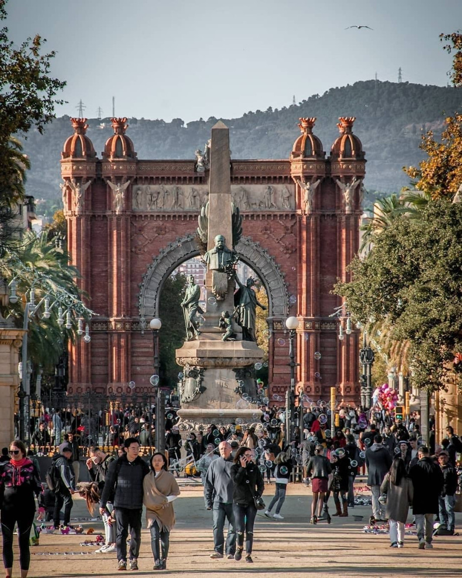 Many people walking along the passage in front of the Arc de Triomf.