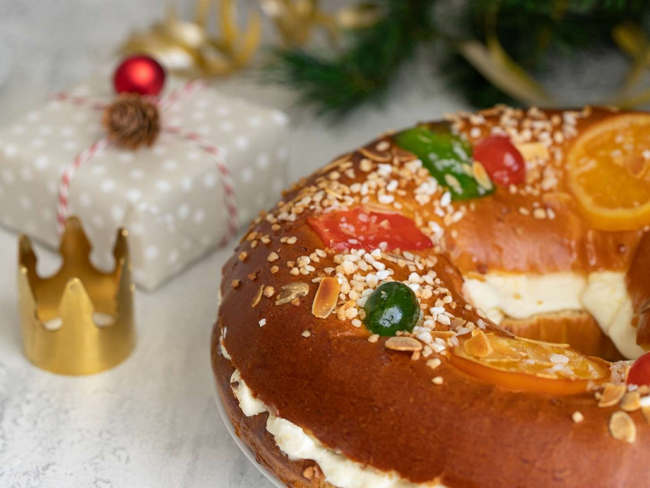 Roscón de Reyes with present and small crown in background.