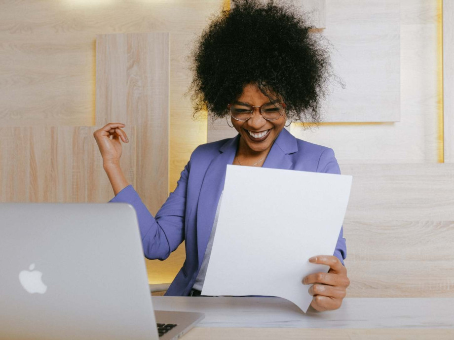 Woman looking at paper report looking very happy.