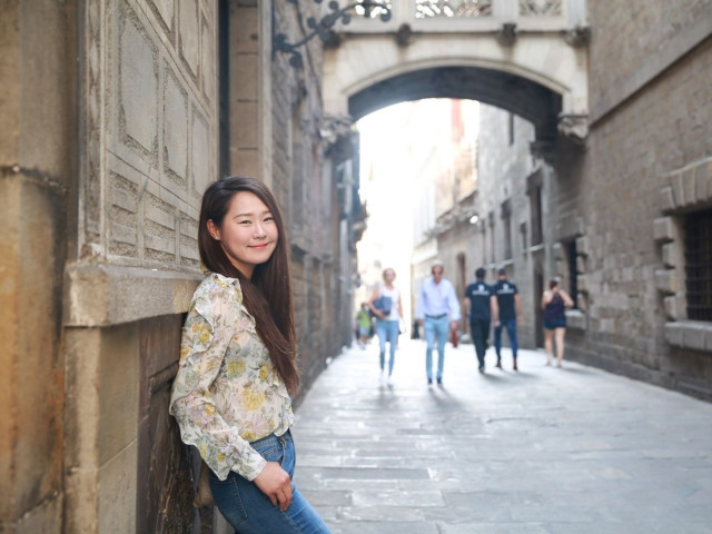 Student leaning against wall in front of the arch on Carrer del Bisbe in Barcelona